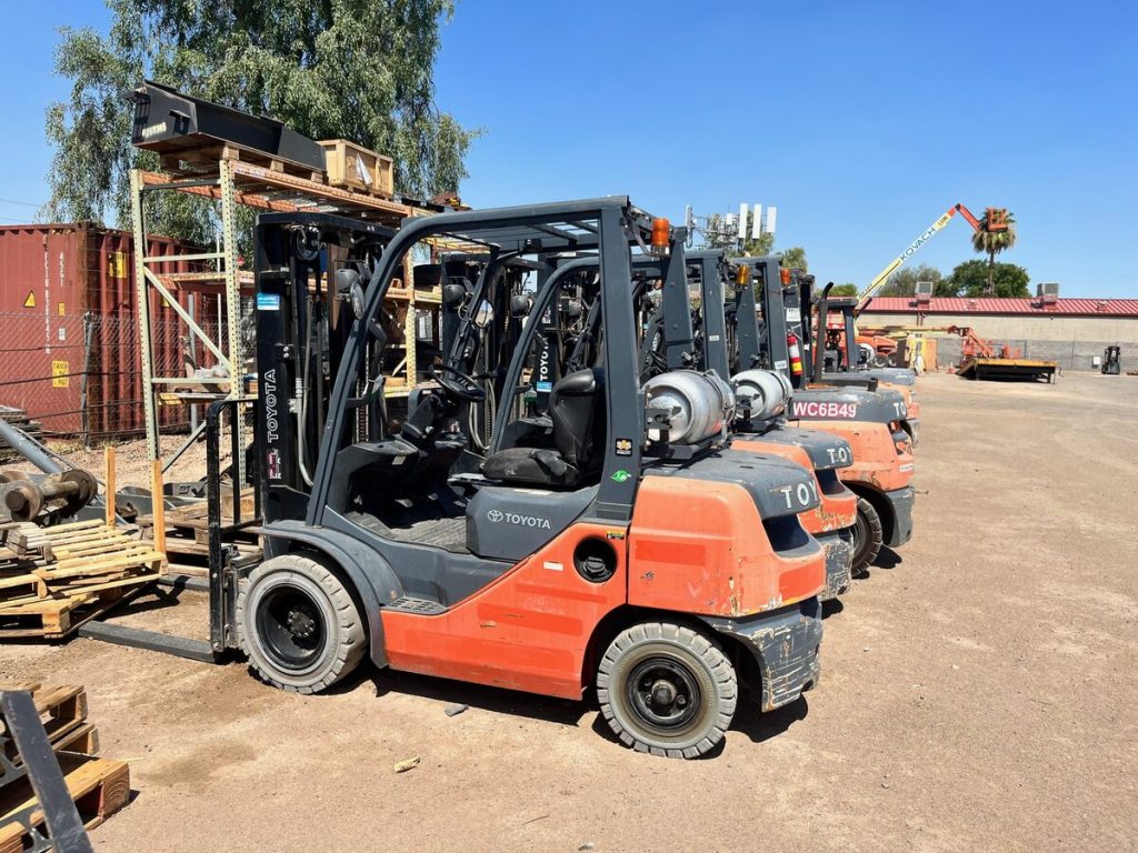 Row of used Toyota propane forklifts parked in an equipment yard