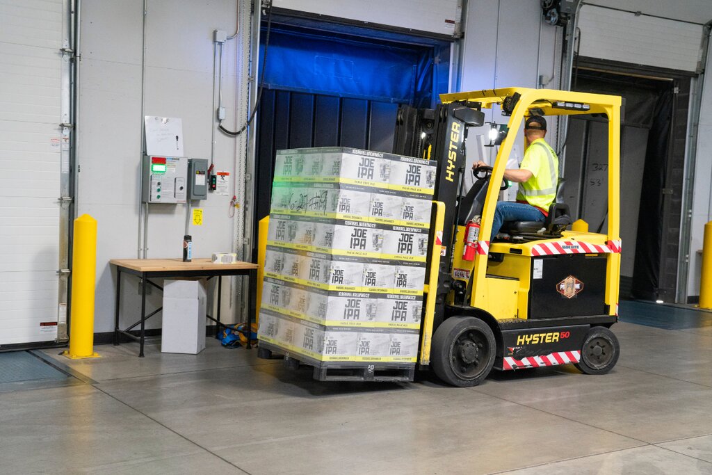 Electric forklift moving a shrink-wrapped pallet toward a warehouse loading dock door