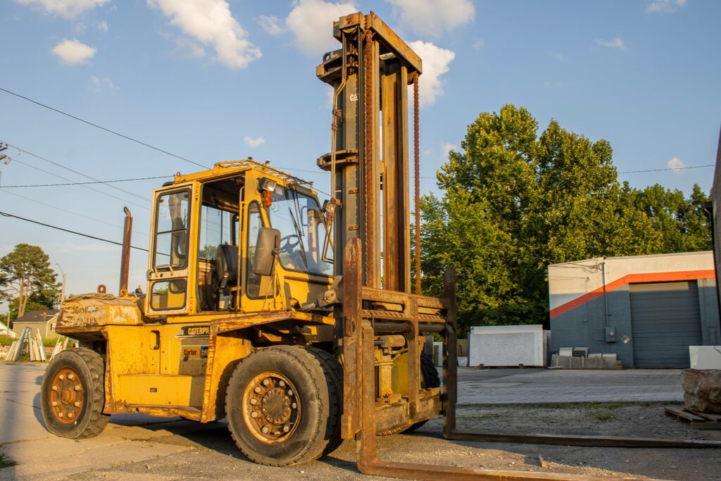 Heavy-capacity Caterpillar forklift with a tall mast parked in an outdoor yard