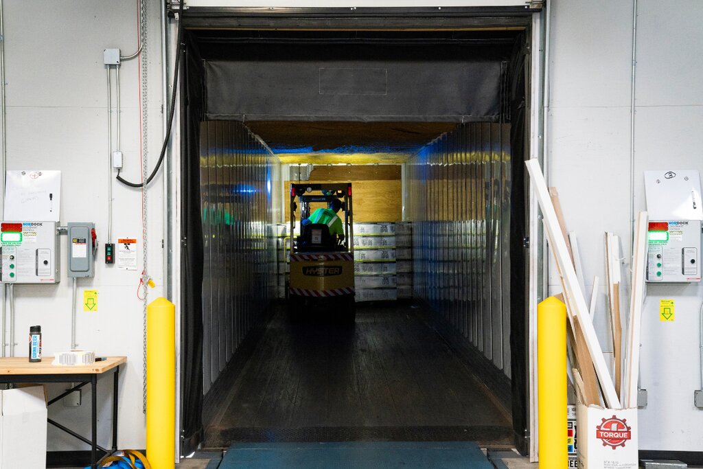 Forklift driving into a trailer at a warehouse loading dock
