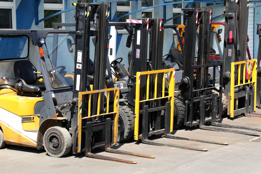 Row of used forklifts parked side by side on an equipment lot